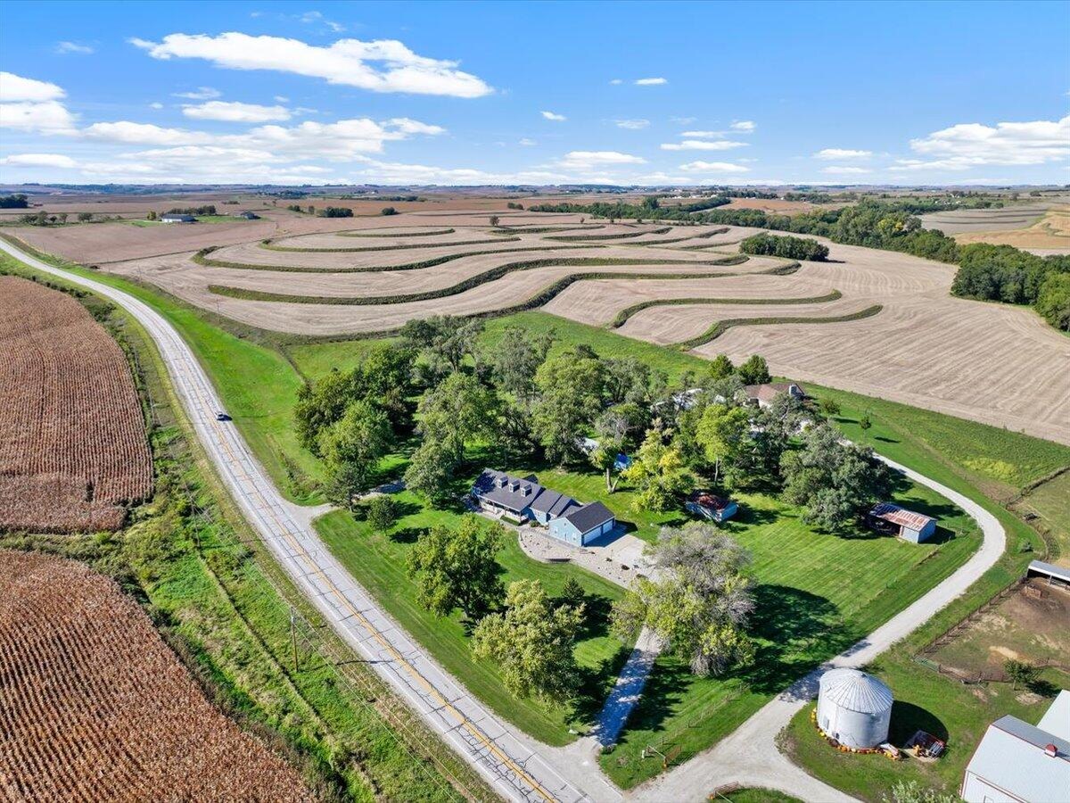Aerial view of a Southwest Iowa acreage with a home, outbuildings, and a grain bin surrounded by terraced farm fields